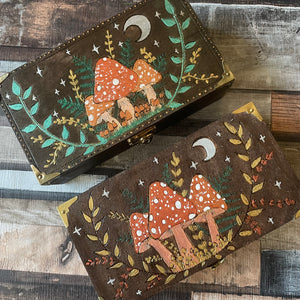 Wooden boxes with mushrooms and leaf designs, woodburned and painted in metallic paints with a dark oak background 